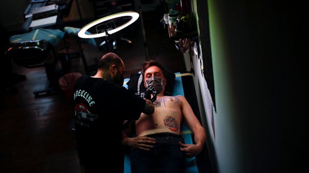 FILE - A man, wearing a protective face mask to prevent the spread of coronavirus, is tattooed at Paul and Friends tattoo parlour in downtown Brussels, March 26, 2021. The European Union is imposing restrictions on the inks that tattoo artists can us