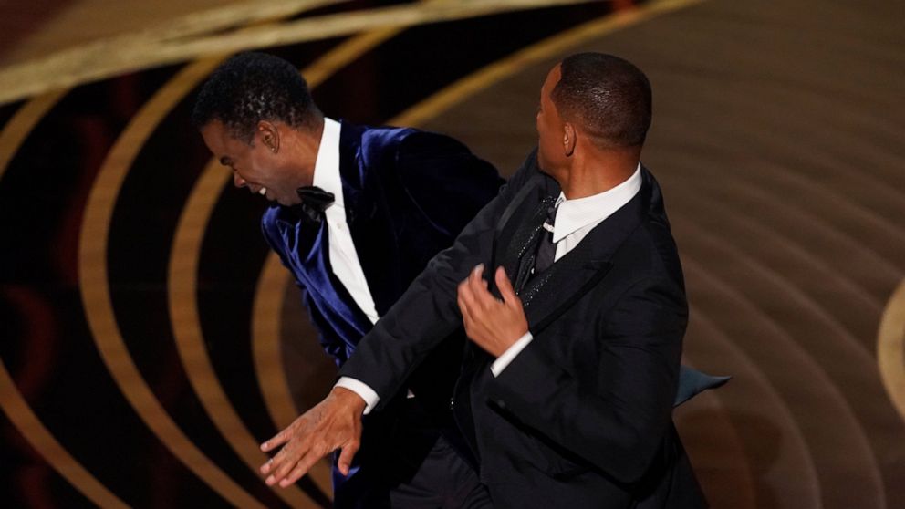Will Smith, right, hits presenter Chris Rock on stage while presenting the award for best documentary feature at the Oscars on Sunday, March 27, 2022, at the Dolby Theatre in Los Angeles. (AP Photo/Chris Pizzello)