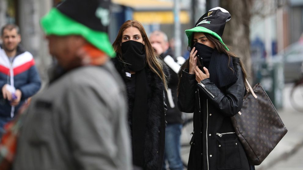 Tourists cover their faces in Dublin city centre, Tuesday March 17, 2020. The St Patrick's Day parades across Ireland were cancelled due to the outbreak of Covid-19 virus. For most people, the new COVID-19 coronavirus causes only mild or moderate sym