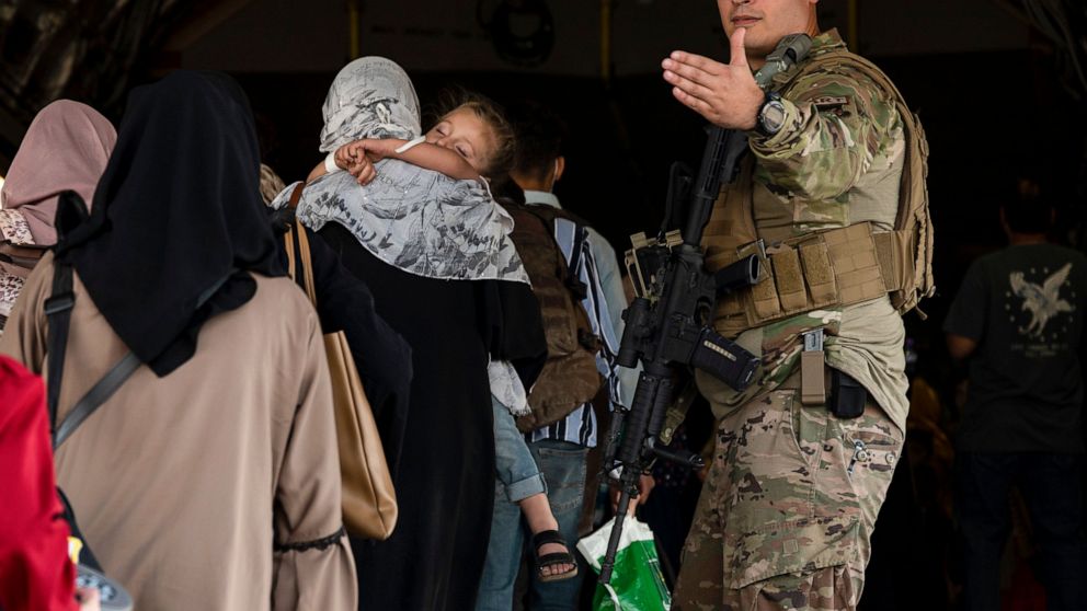 In this image provided by the U.S. Air Force, a U.S. Air Force Airman guides evacuees aboard a U.S. Air Force C-17 Globemaster III at Hamid Karzai International Airport in Kabul, Afghanistan, Tuesday, Aug. 24, 2021. (Senior Airman Taylor Crul/U.S. Ai