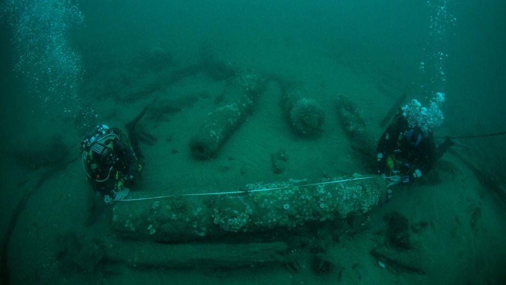 In this undated photo provided by Norfolk Historic Shipwrecks, Julian And Lincoln Barnwell measure the cannon found on the HMS Gloucester in 2007. Excavators and historians are telling the world about the wreck of a royal warship that sank in 1682 wh