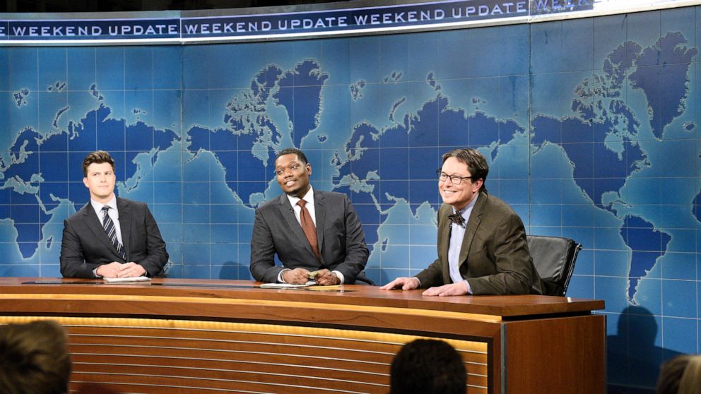 This image released by NBC shows, from left, Colin Jost, Michael Che, and host Elon Musk as financial expert Lloyd Ostertag during the "Weekend Update" sketch on "Saturday Night Live," in New York on May 8, 2021. (Will Heath/NBC via AP)