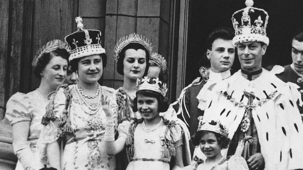 FILE - Princess Elizabeth, centre, age 11, appears on the balcony of Buckingham Palace after the coronation of her father, King George VI, right, in London, May 12, 1937. Queen Elizabeth II, Britain’s longest-reigning monarch and a rock of stability 