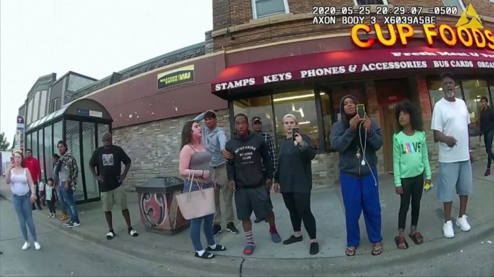 FILE - This May 25, 2020, file image from a police body camera shows bystanders including Darnella Frazier, third from right filming, as former Minneapolis police officer Derek Chauvin was recorded pressing his knee on George Floyd's neck for several