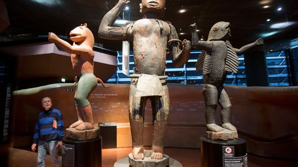 In this Friday, Nov. 23, 2018 file photo a visitor looks at wooden royal statues of the Dahomey kingdom, dated 19th century, at Quai Branly museum in Paris, France. France will return 26 African artworks to Benin later this month as part of long-prom