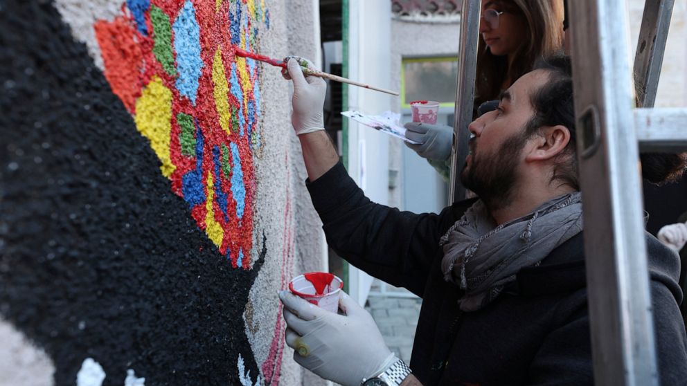 Evacuated Afghan artists paint a mural in Albania’s capital