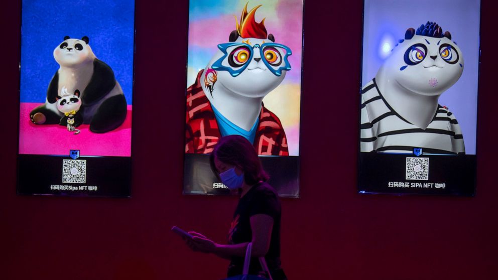 FILE - A visitor wearing a face mask walks past artwork displayed at an NFT (non-fungible token)-themed coffee shop at the China International Fair for Trade in Services (CIFTIS) in Beijing, Sept. 3, 2022. Fidelity Charitable, the nation's largest gr
