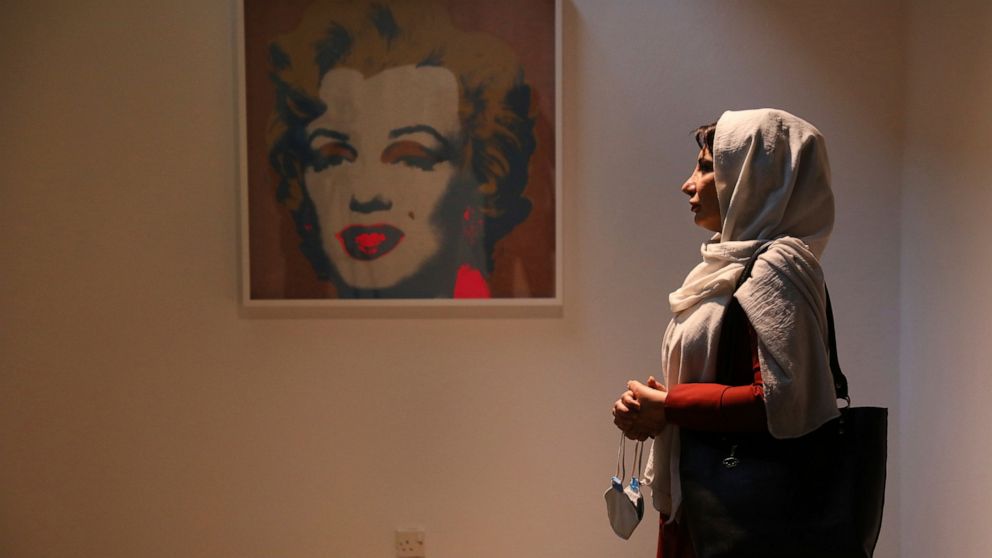 Fatemeh Rezaei, a retired teacher, stands next to Marilyn Monroe portrait by American artist Andy Warhol at Tehran Museum of Contemporary Art in Tehran, Iran on Oct. 19, 2021. Iranians are flocking to Tehran's contemporary art museum to marvel at Ame