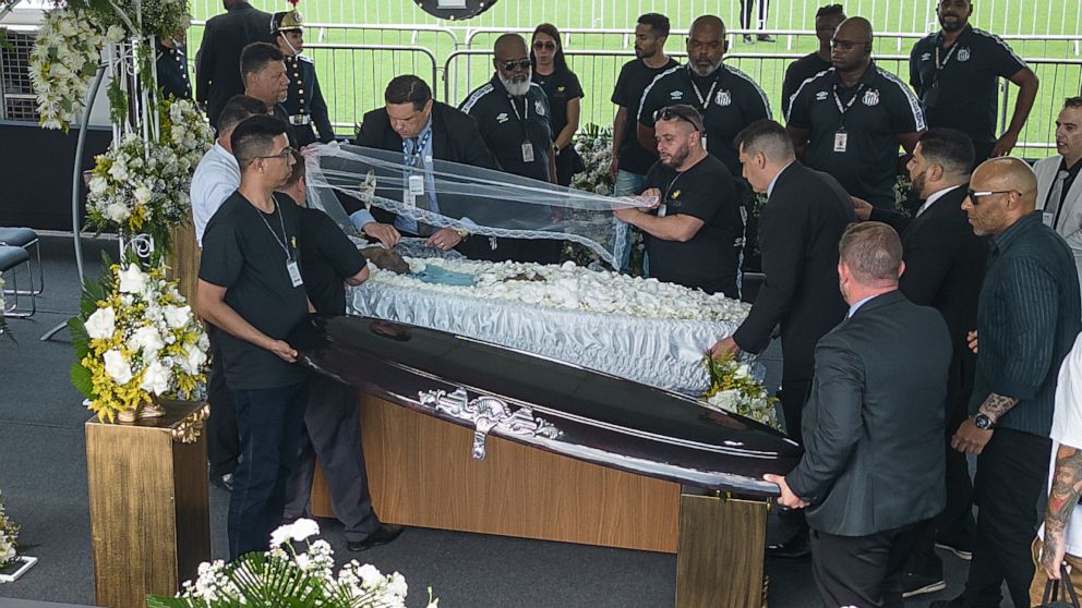 Funeral workers uncover the coffin of the late Brazilian soccer great Pele as he lies in state on the pitch during his wake at Vila Belmiro stadium in Santos, Brazil, Monday, Jan. 2, 2023. (AP Photo/Matias Delacroix)