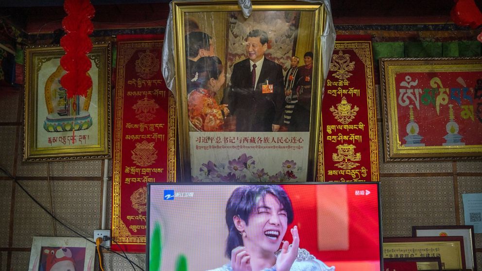 FILE - In this June 4, 2021, file photo, a television shows a broadcast of a Chinese talk show program as it sits beneath a photo of Chinese President Xi Jinping in a home converted into a tourist homestay in Zhaxigang village near Nyingchi in wester