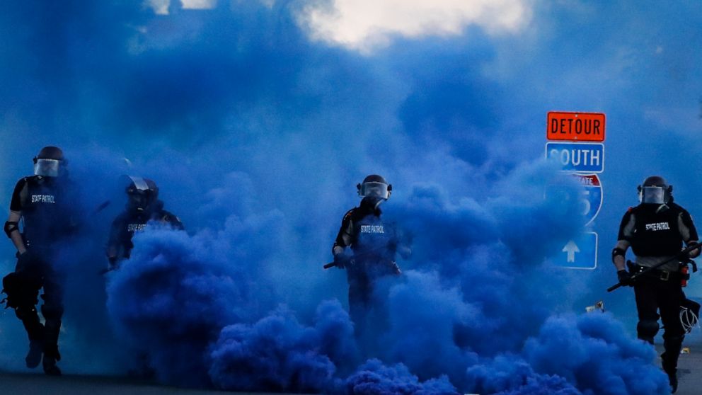 Police in riot gear walk through a cloud of blue smoke as they advance on protesters near the Minneapolis 5th Precinct, Saturday, May 30, 2020, in Minneapolis. Protests continued following the death of George Floyd, who died after being restrained by