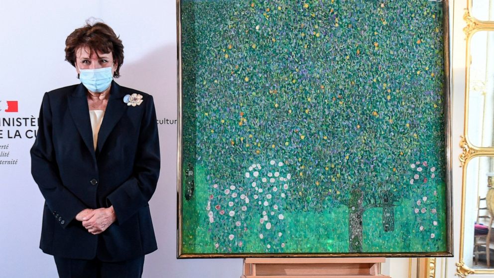 French Culture Roselyne Bachelot poses next to a spoiled oil painting by Gustav Klimt painted between in 1905 called"Rosebushes under the Trees," during a ceremony at the Orsay museum in Paris, Monday, March 15, 2021. The French government hands over