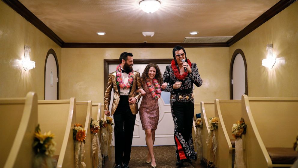 FILE - Elvis impersonator Brendan Paul, right, walks down the aisle during a wedding ceremony for Katie Salvatore, center, and Eric Wheeler at the Graceland Wedding Chapel in Las Vegas. Authentic Brands Group (ABG) sent cease-and-desist letters earli
