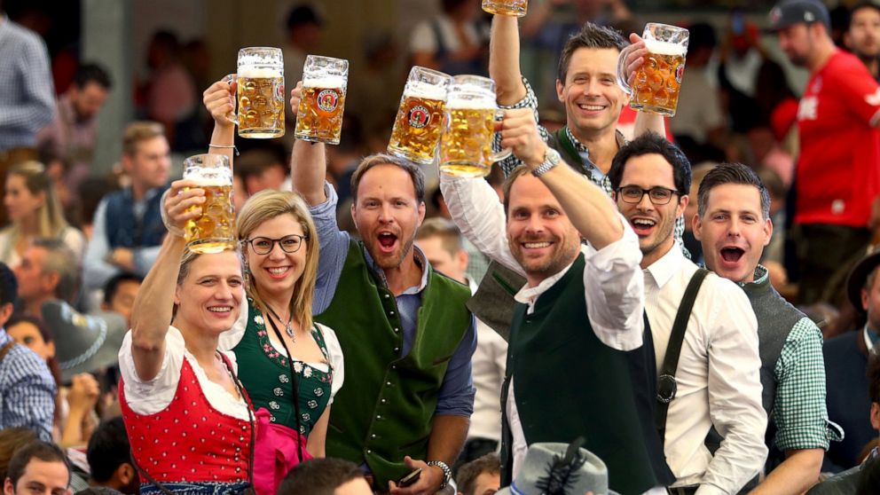 FILE - In this Saturday, Sept. 21, 2019 file photo, visitors lift glasses of beer during the opening of the 186th 'Oktoberfest' beer festival in Munich, Germany. The annual Oktoberfest festival is finally on again for this fall, following a two-year 