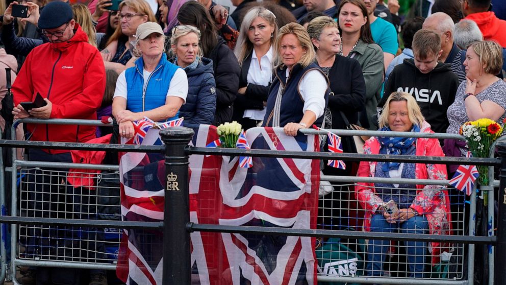 People wait near to Buckingham Palace ahead of the ceremonial procession of the coffin of Queen Elizabeth II, from Buckingham Palace to Westminster Hall, in London, Wednesday Sept. 14, 2022. The Queen will lie in state in Westminster Hall for four fu