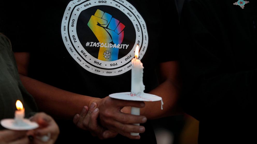 FILE - Movie industry worker Hailey Josselyn, wearing a t-shirt of the International Alliance of Theatrical Stage Employees (IATSA), holds a candle during a vigil to honor cinematographer Halyna Hutchins in Albuquerque, N.M., on Oct. 23, 2021. Hutchi