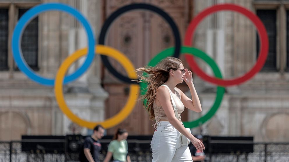 FILE - A woman passes by the Olympic rings at the City Hall in Paris, Monday, July 25, 2022. Paris Olympic organizers appointed prize-winning French theater director Thomas Jolly on Wednesday Sept. 21, 2022 to direct the opening and closing ceremonie