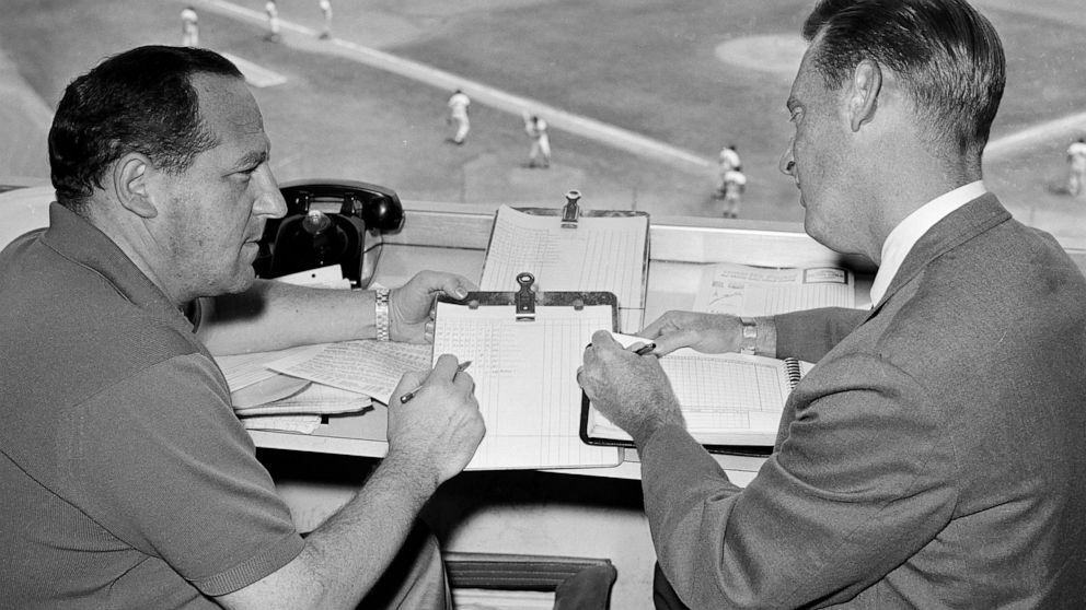 FILE - Allan Roth, left, statistician of the Los Angeles Dodgers, sits in the booth with broadcaster Vin Scully in August 1963 in Los Angeles. Scully, whose dulcet tones provided the soundtrack of summer while entertaining and informing Dodgers fans 