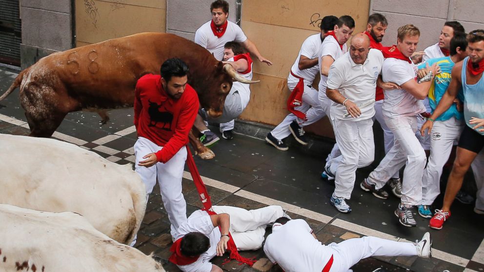 PHOTO: A reveler is tossed by a Miura fighting bull as other fall during the running of the bulls at the San Fermin festival, in Pamplona, Spain, on July 14, 2014.