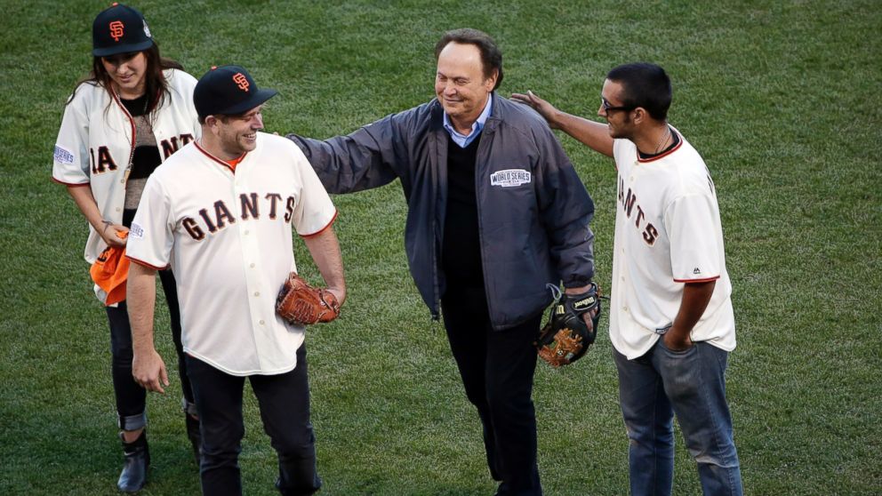 Robin Williams' son Zak Williams gets a pat on the back from Billy Crystal after Zak threw out the ceremonial first pitch as his siblings Zelda and Cody look on before Game 5 of baseball's World Series between the Kansas City Royals and the San Francisco Giants, Oct. 26, 2014, in San Francisco.
