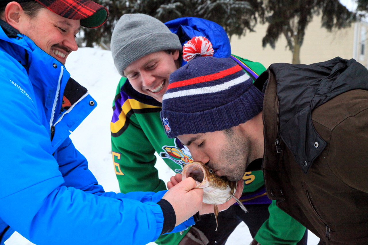 PHOTO: Jared Olson and ABC News' Michael Koenigs watch as Michael Huberman kisses an eelpout for good luck before Super Bowl LII in Minneapolis.