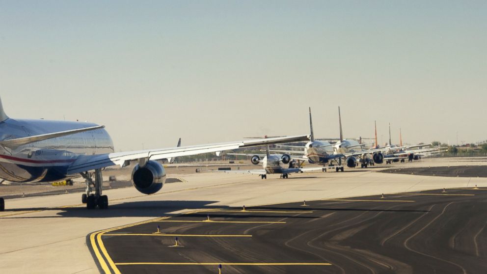 Commercial jets wait in line on an airport runway.