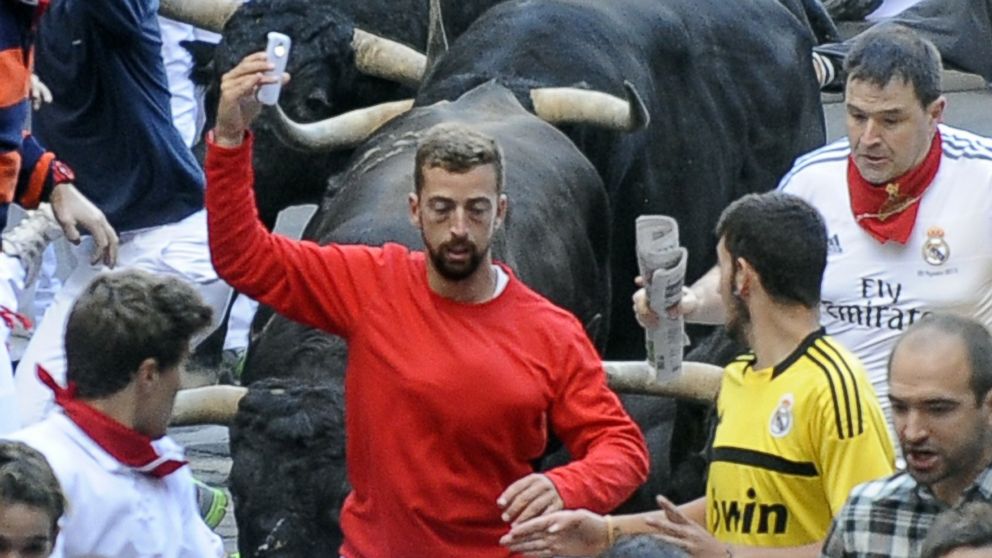 PHOTO: A participant runs in front of Jandilla's bulls as he takes a "selfie" during the fifth bull-run of the San Fermin Festival in Pamplona, northern Spain, on July 11, 2014.