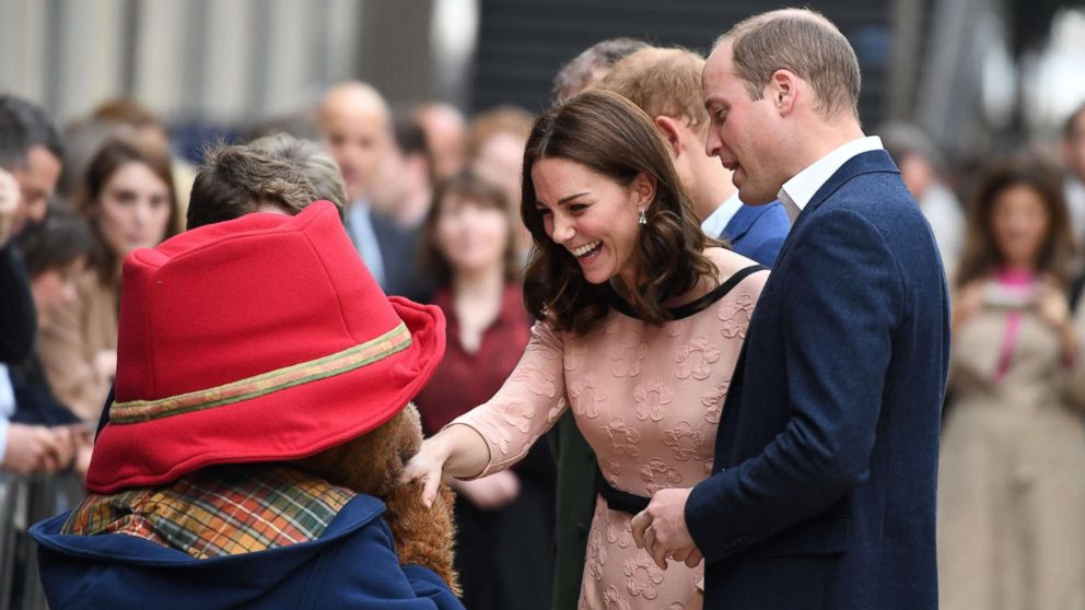 Britain's Catherine, Duchess of Cambridge shakes hands with a person in a Paddington Bear outfit along with her husband Britain's Prince William, Duke of Cambridge, as they attend a charities event at Paddington train station in London, Oct. 16, 2017.