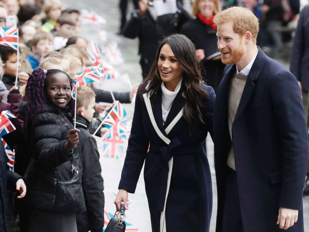 PHOTO: Meghan Markle and Britain's Prince Harry are greeted by flag waving school children as they arrive to take part in an event for young women as part of International Women's Day in Birmingham, central England, March 8, 2018.