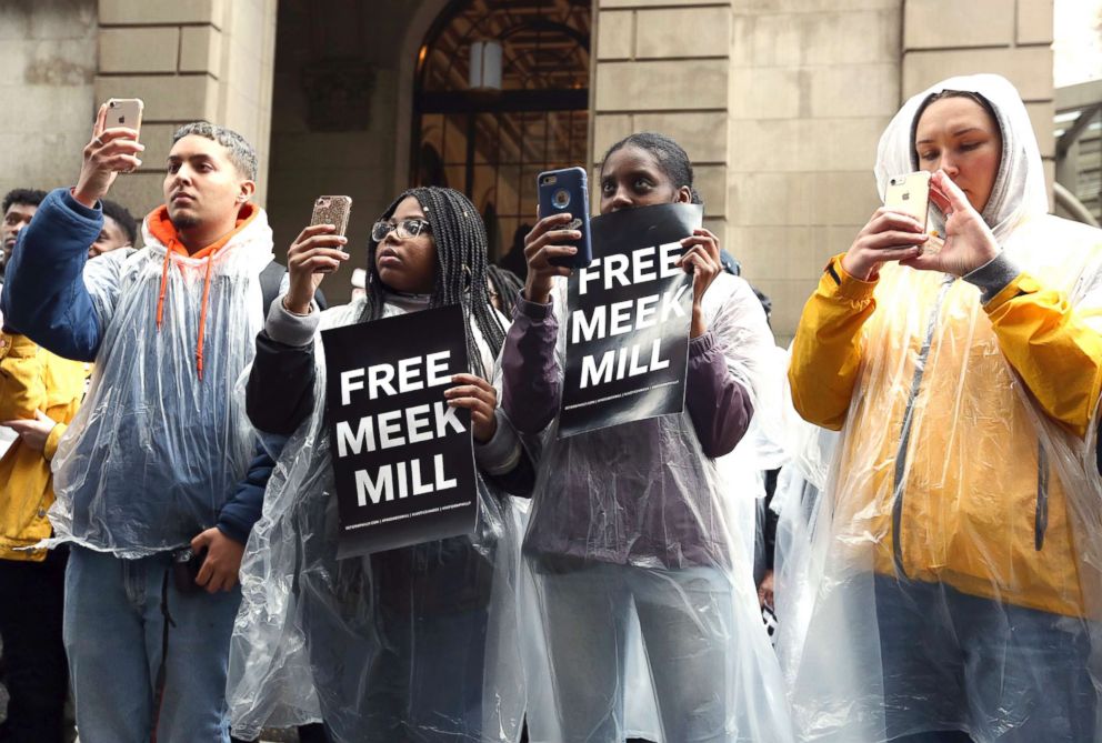 PHOTO: Protesters uses their phones and listen to a speaker in front of a courthouse during a hearing for rapper Meek Mill, April 16, 2018 in Philadelphia. 