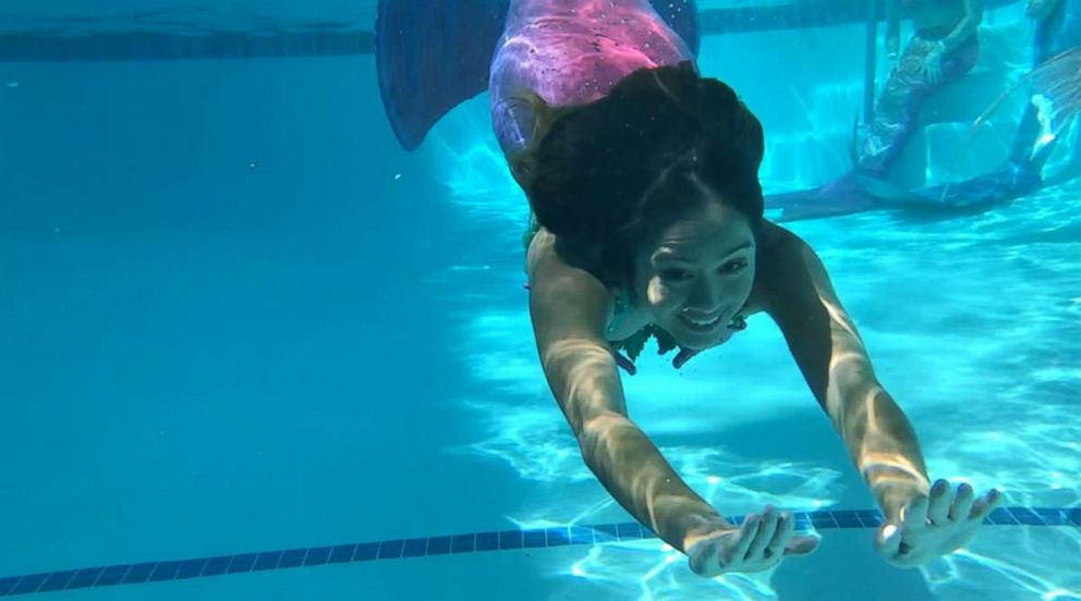 PHOTO: A woman dressed as a mermaid swims with her mermaid tail.