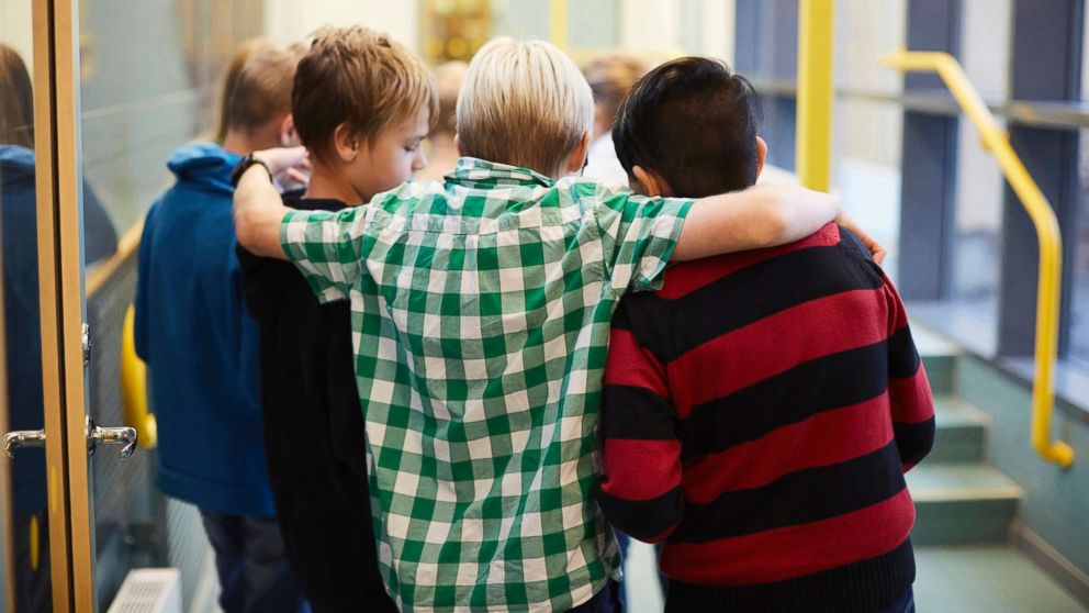 Middle-school aged boys stand in a hallway in an undated stock photo.