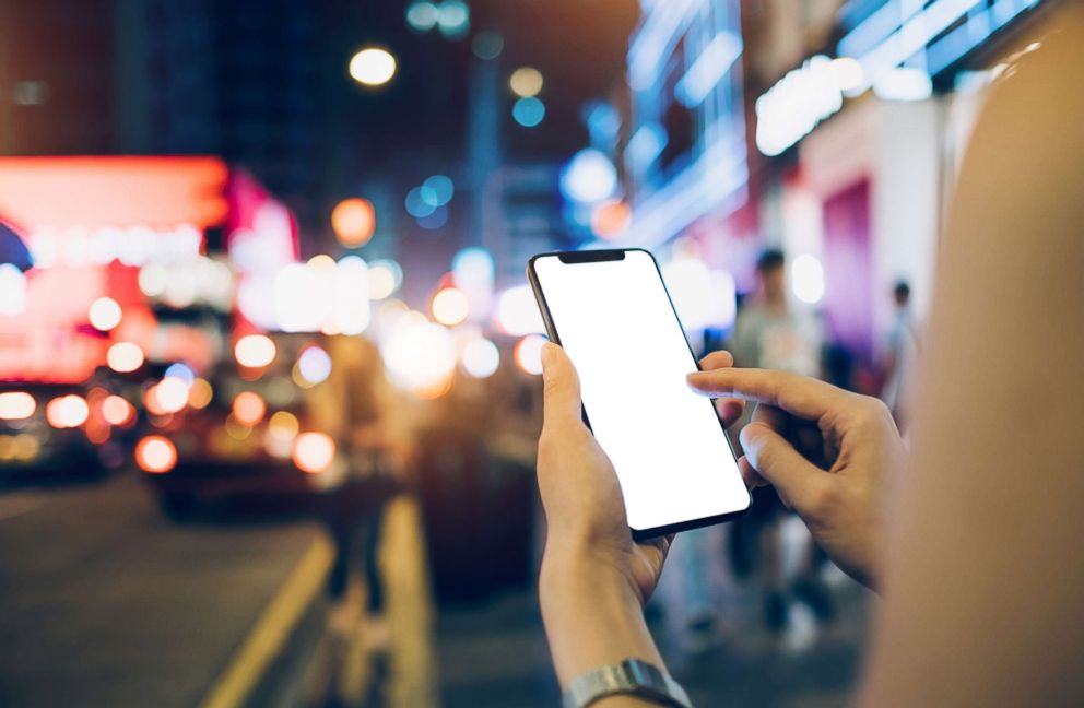 PHOTO: A woman uses her mobile phone for navigating direction in a busy city street.