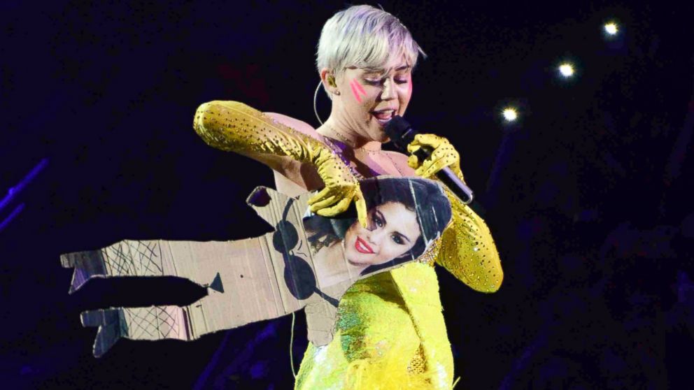 Miley Cyrus holds a cardboard cutout with Selena Gomez's photograph on it during her concert at the Forum in Milan, Italy on June 8, 2014.