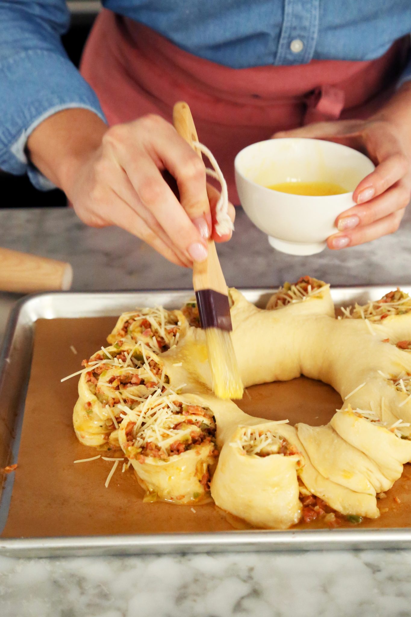 PHOTO: A savory King cake with sausage and cheese gets an egg wash before baking.