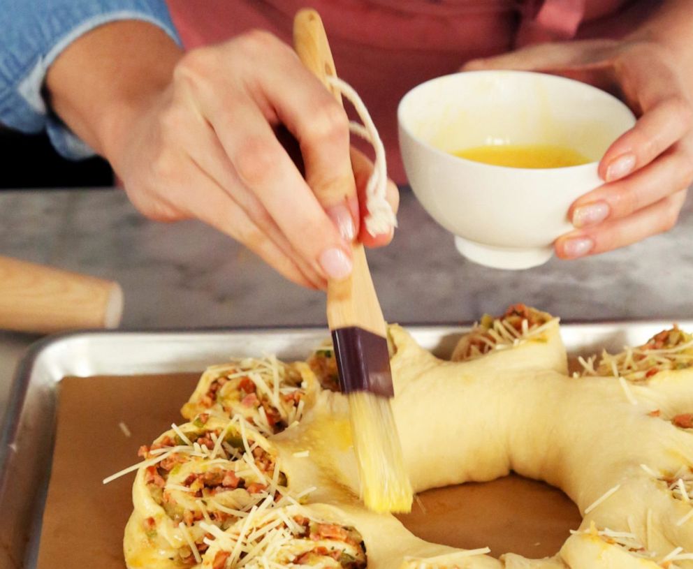 PHOTO: A savory King cake with sausage and cheese gets an egg wash before baking.