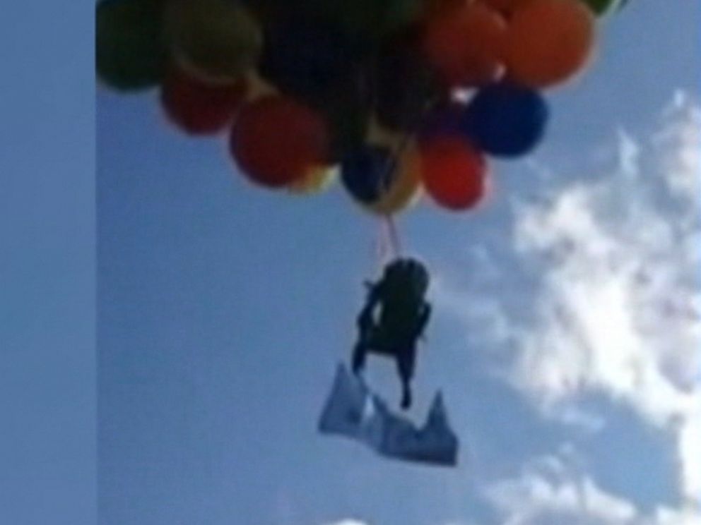 man flies with balloons and lawn chair