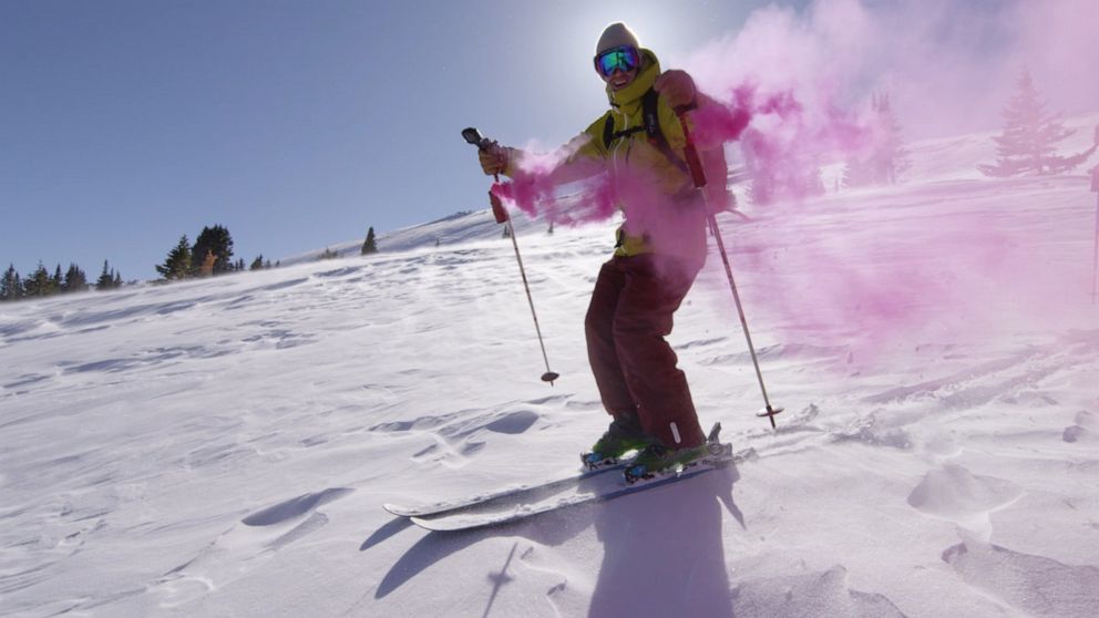 PHOTO: Greg Day skis down a mountain with clouds of pink smoke after finding he and his wife Amanda will have a baby girl.
