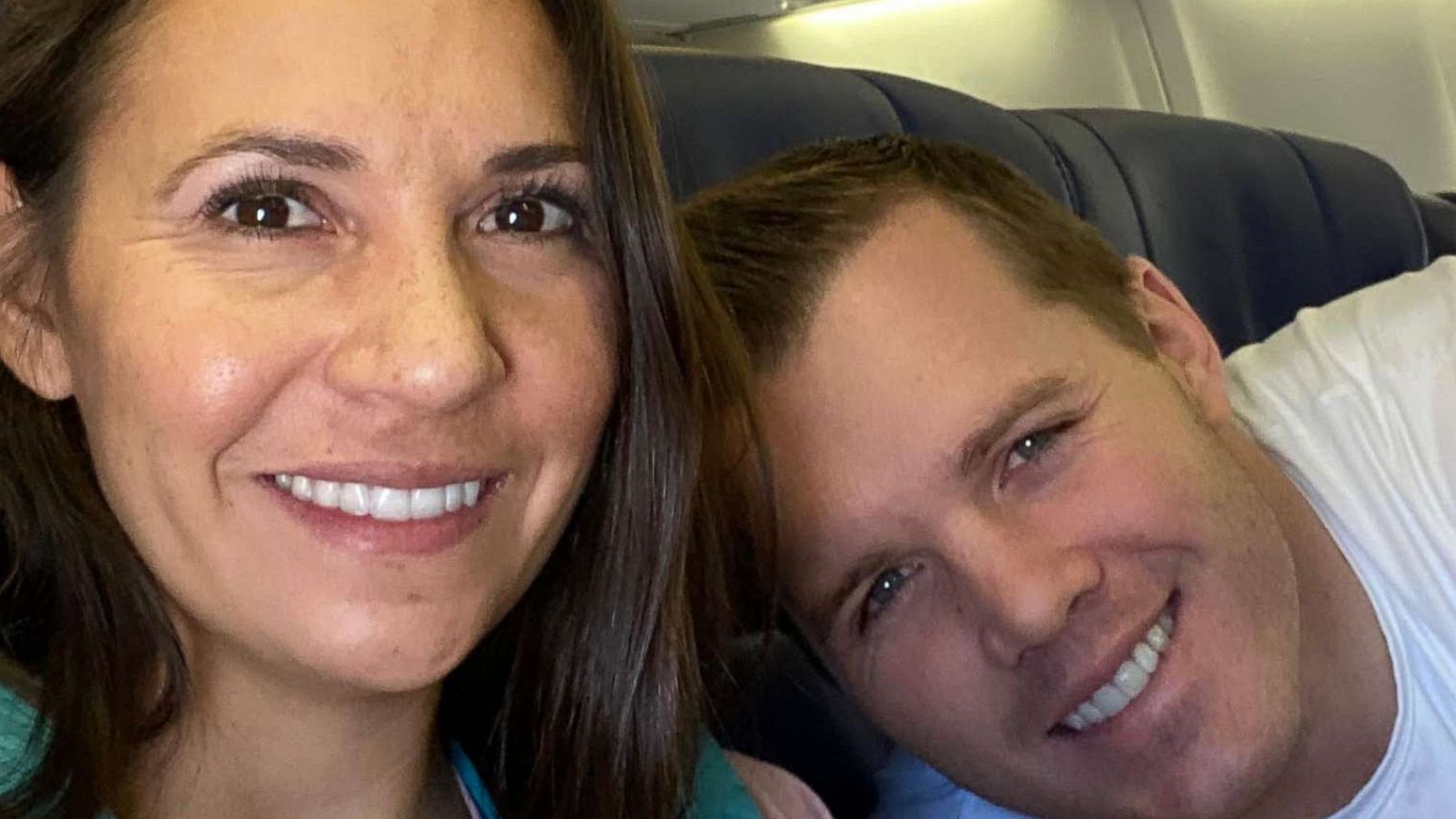 PHOTO: Dustin and Caren Moore with their baby on their flight home after completing her adoption.