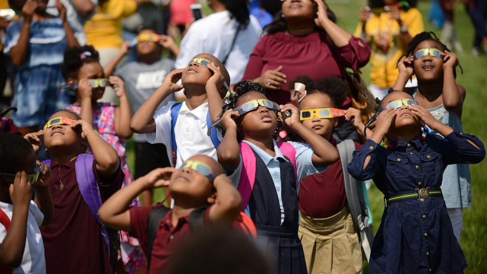 PHOTO: Students at CW Harris Elementary School in SE Washington, D.C., Aug. 21, 2017, use their protective shades to watch the solar eclipse outside their school.