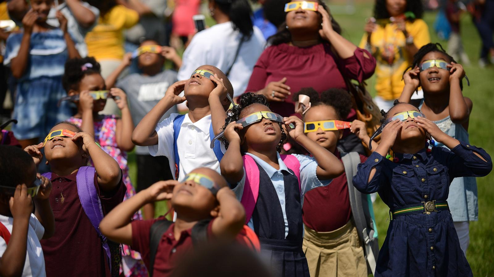 PHOTO: Students at CW Harris Elementary School in SE Washington, D.C., Aug. 21, 2017, use their protective shades to watch the solar eclipse outside their school.