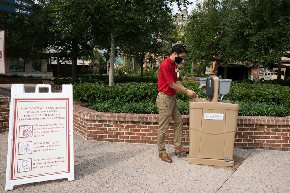 Prior to the May 20, 2020, reopening of Disney Springs a Disney cast member cleans his hands using a new hand-washing station installed at the shopping, dining and entertainment district. 