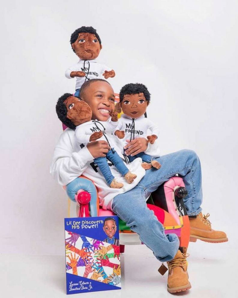 PHOTO: Demetrius poses with three of the My Friend dolls and his book. 