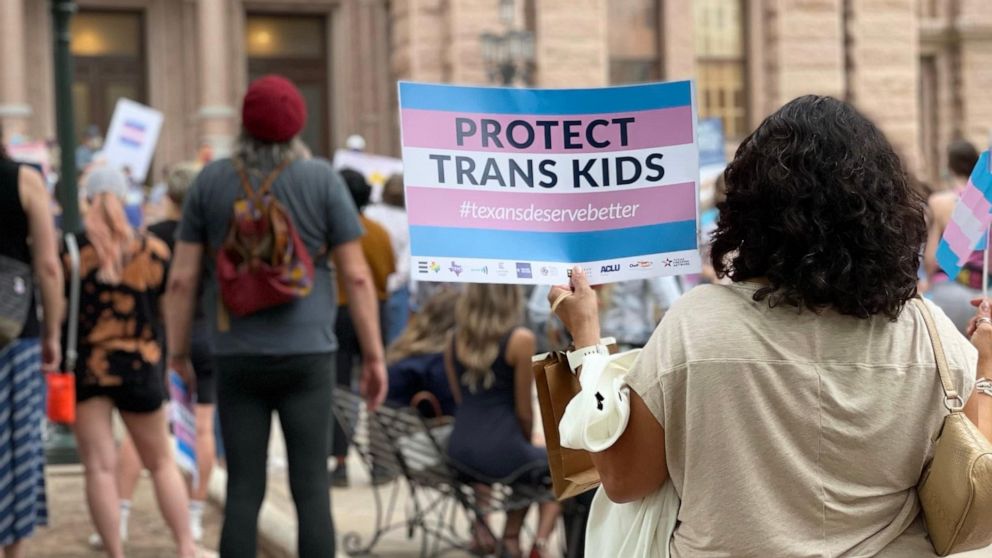 Camille Rey holds a sign that reads "Protect Trans Kids."