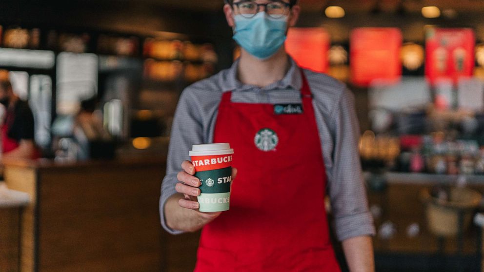PHOTO: A Starbucks employee holds out a coffee in the seasonal holiday cup.