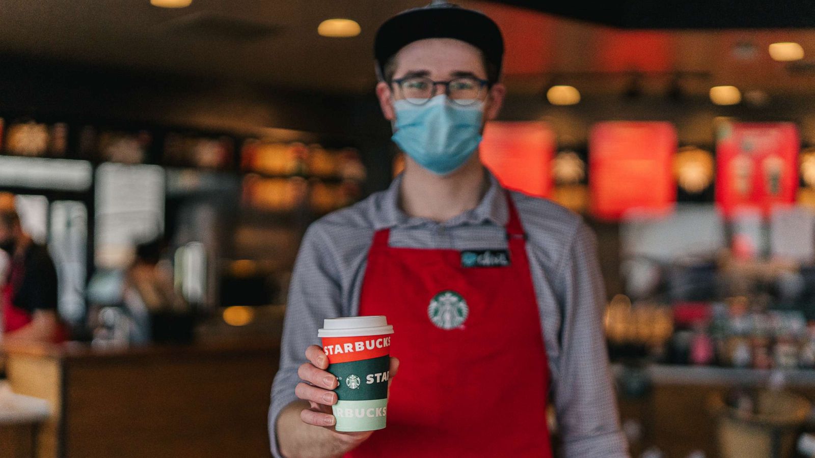 PHOTO: A Starbucks employee holds out a coffee in the seasonal holiday cup.