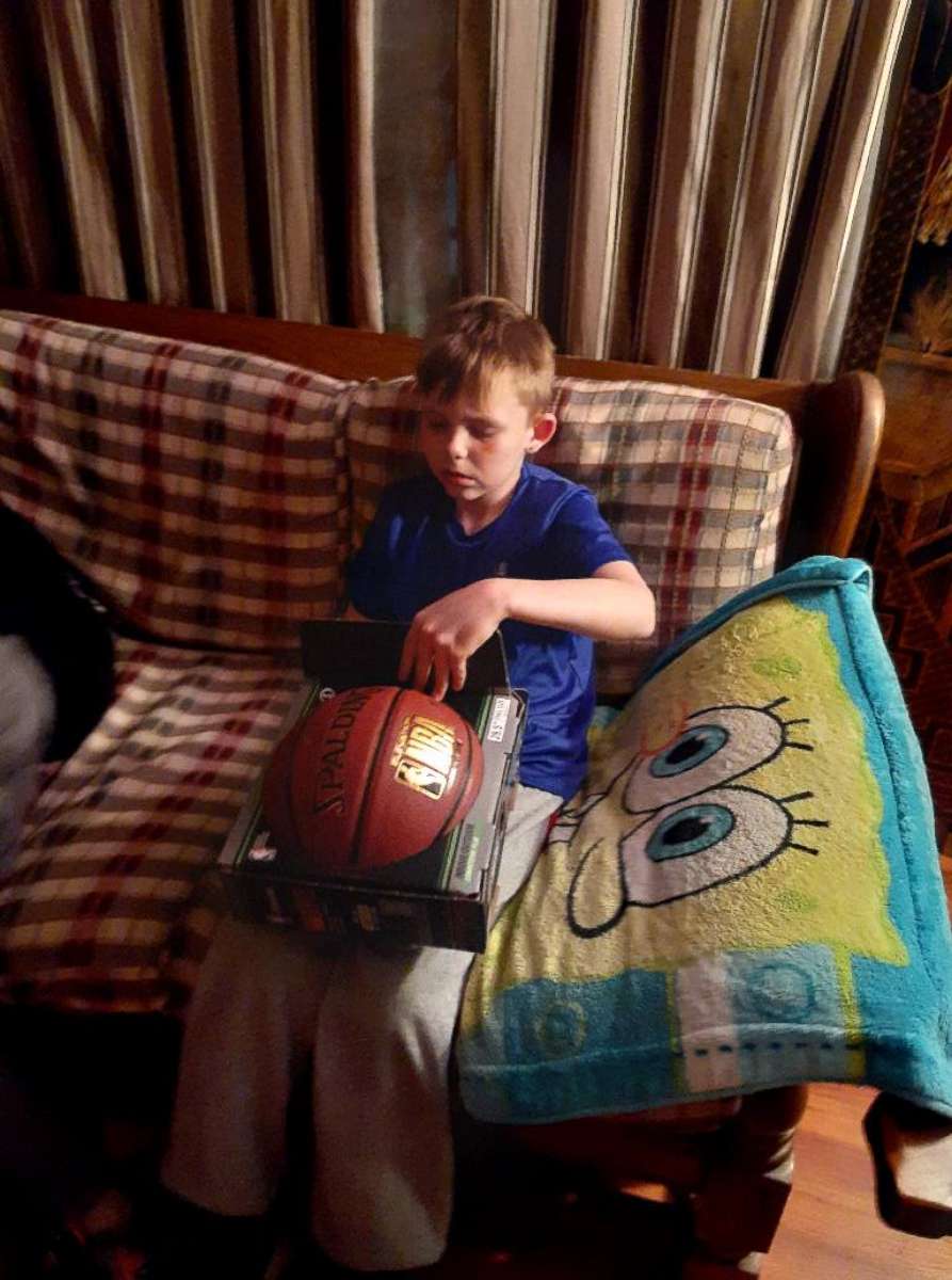 PHOTO: Boy holding basketball gifted by FedEx driver.