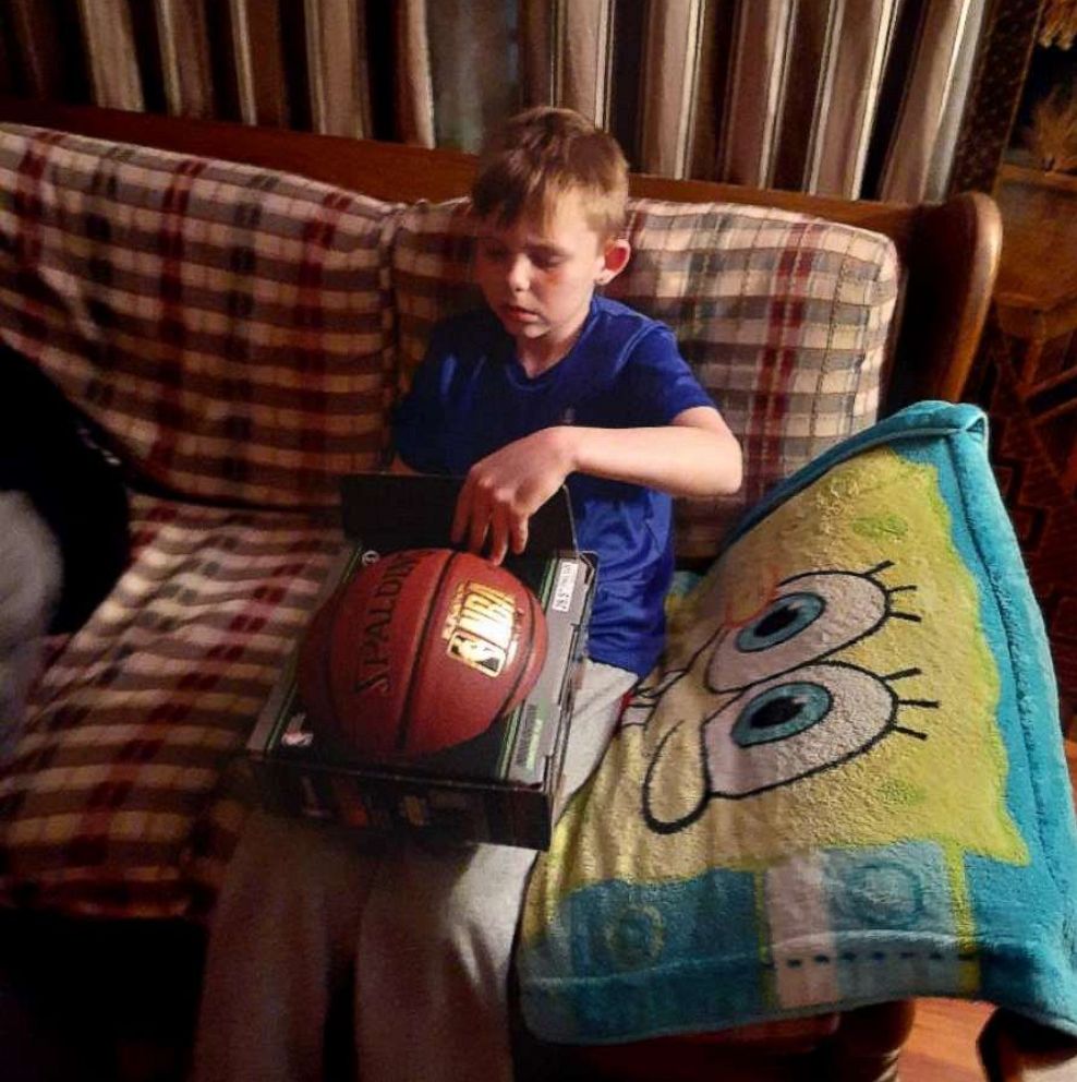 PHOTO: Boy holding basketball gifted by FedEx driver.