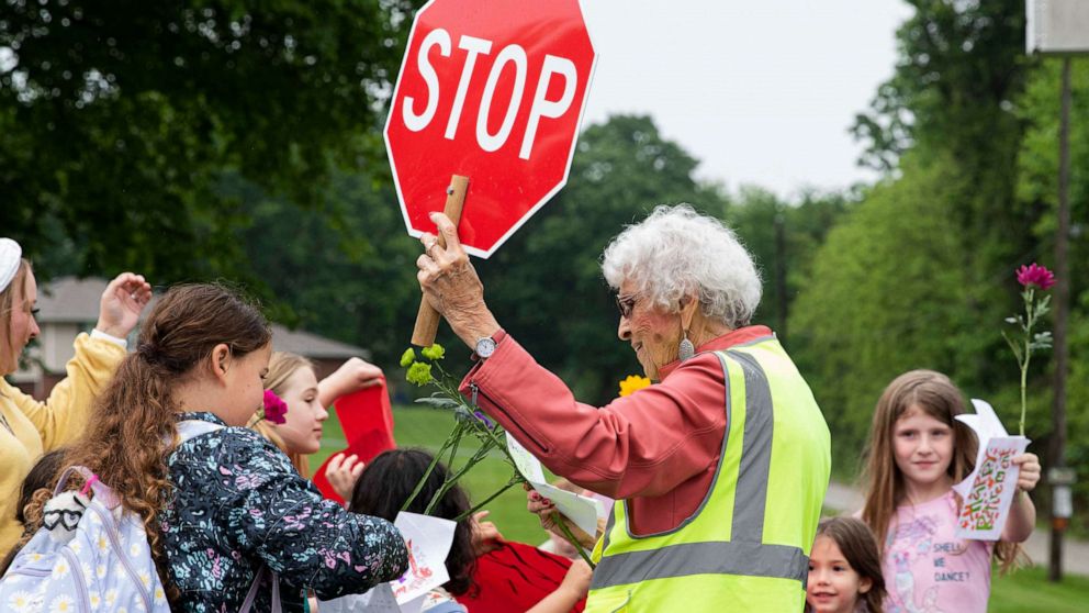 PHOTO: Students greet crossing guard Sandra Bellew with hugs, handwritten signs and flowers on May 19, 2023, ahead of her retirement.