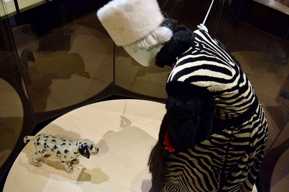 PHOTO: An outfit worn by Glenn Close as Cruella De Vil from 1996’s 101 Dalmatians, designed by Anthony Powell, with a prop puppy used in the film